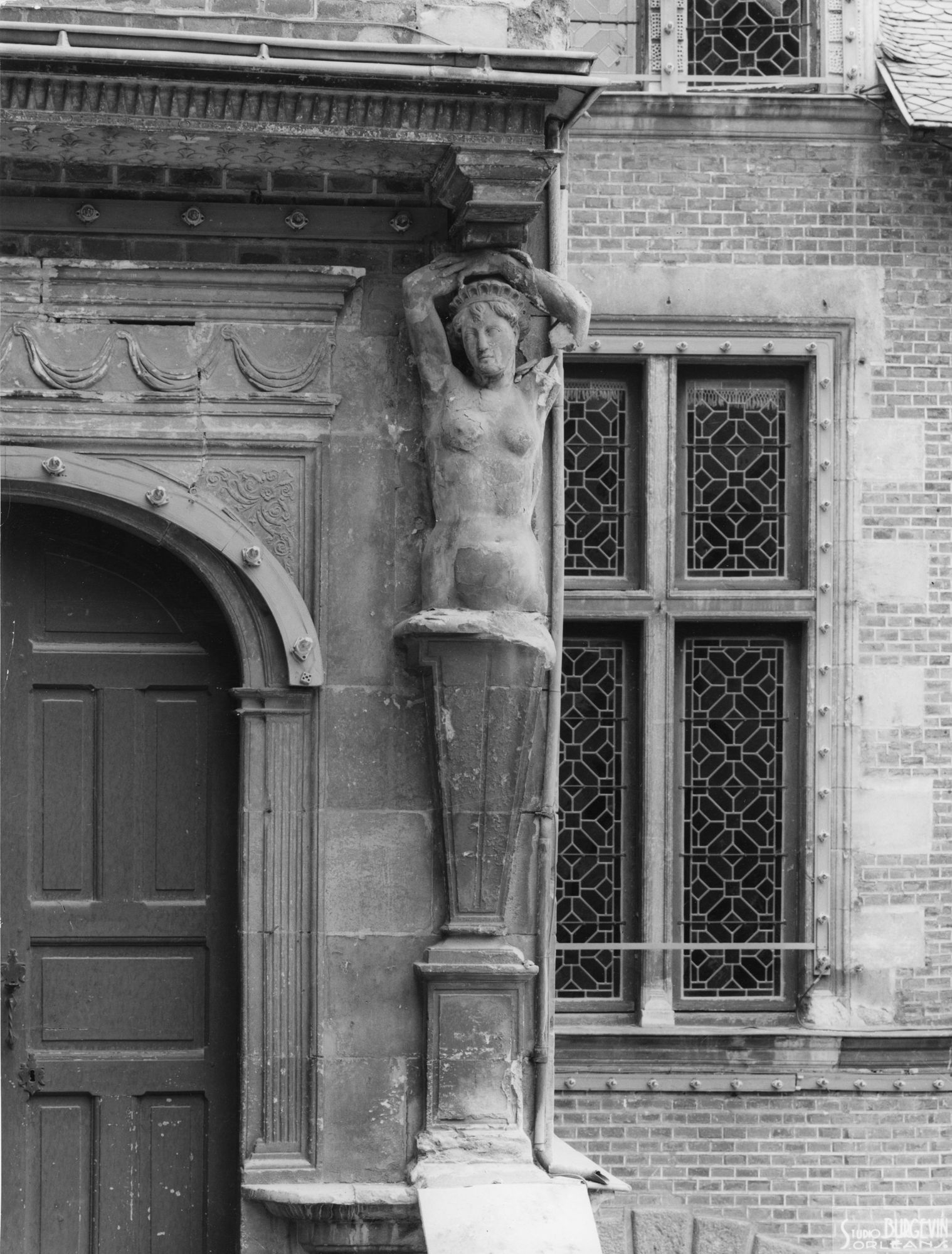Hôtel Groslot, place de l'Etape : caryatide d’un pilier de porte. Etat de dégradation avancée. Vue de face. 1965. Auteur, Studio Roger Burgevin. AMO, 3Fi413.